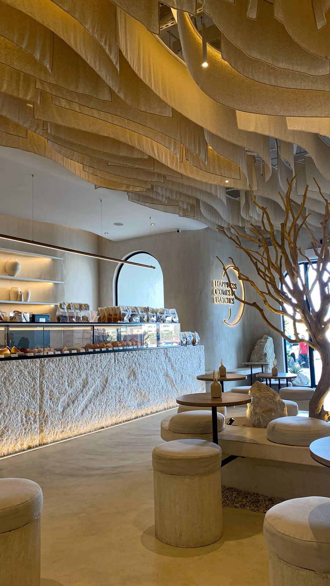 Artisan patisserie with draped fabric ceiling, stone counter and warm gold lighting
